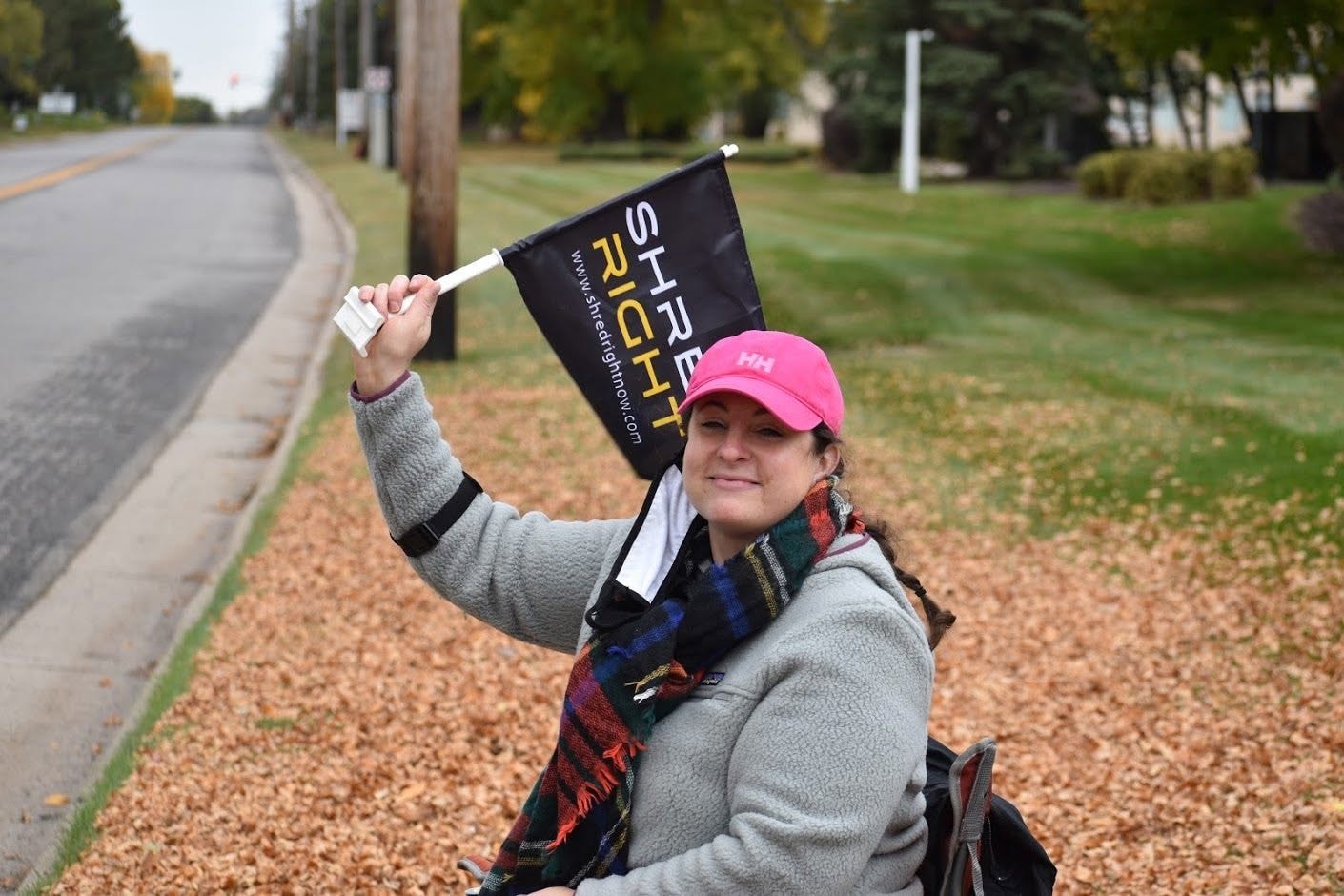 Volunteer waving Shred Right flag wearing pink hat